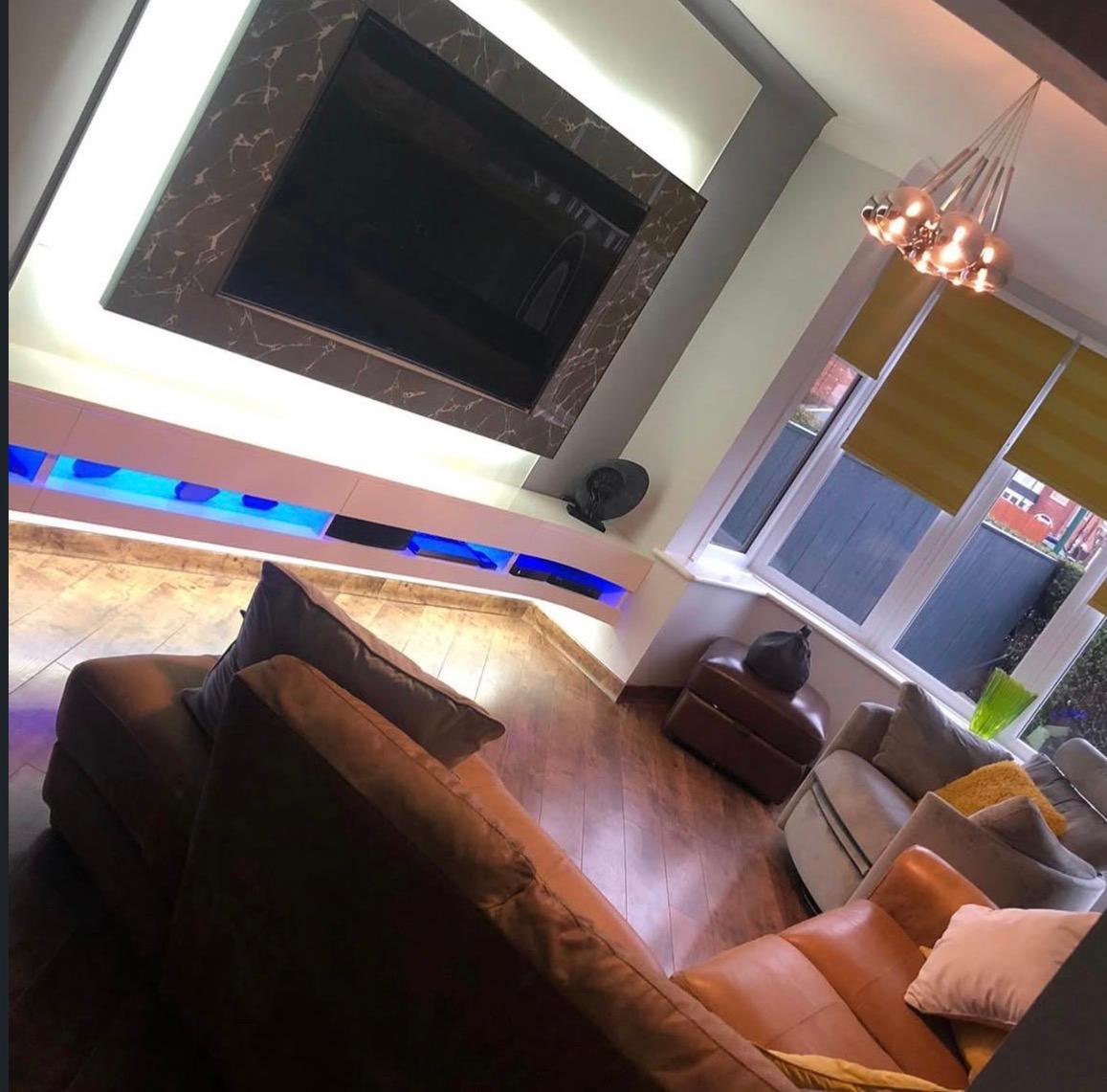 Living room view showing the bespoke media wall and illuminated floating media unit within the wider space.