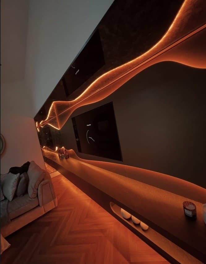 Close angled view of the media wall's flowing illuminated detail shown in warm orange LED light.