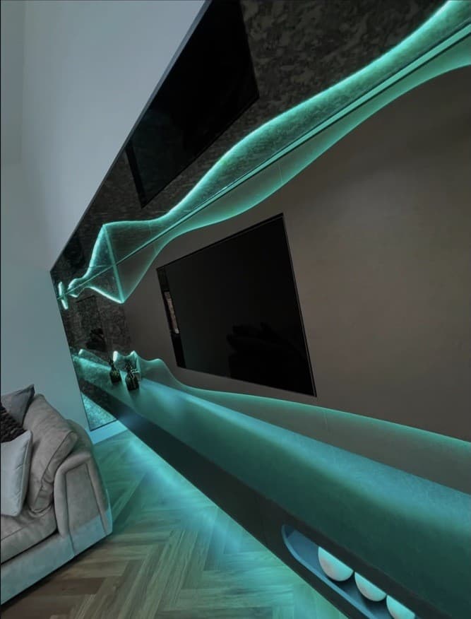Angled detail of the media wall showing the curved illuminated upper and lower features in teal light.
