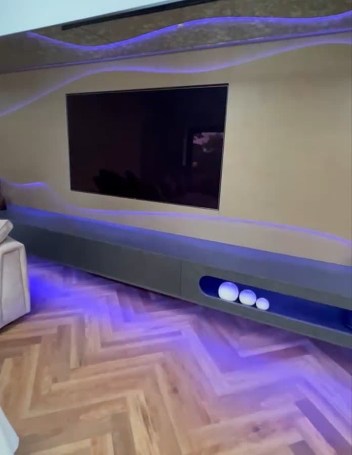Front detail of the media wall and floating unit illuminated with blue and violet LED lighting.