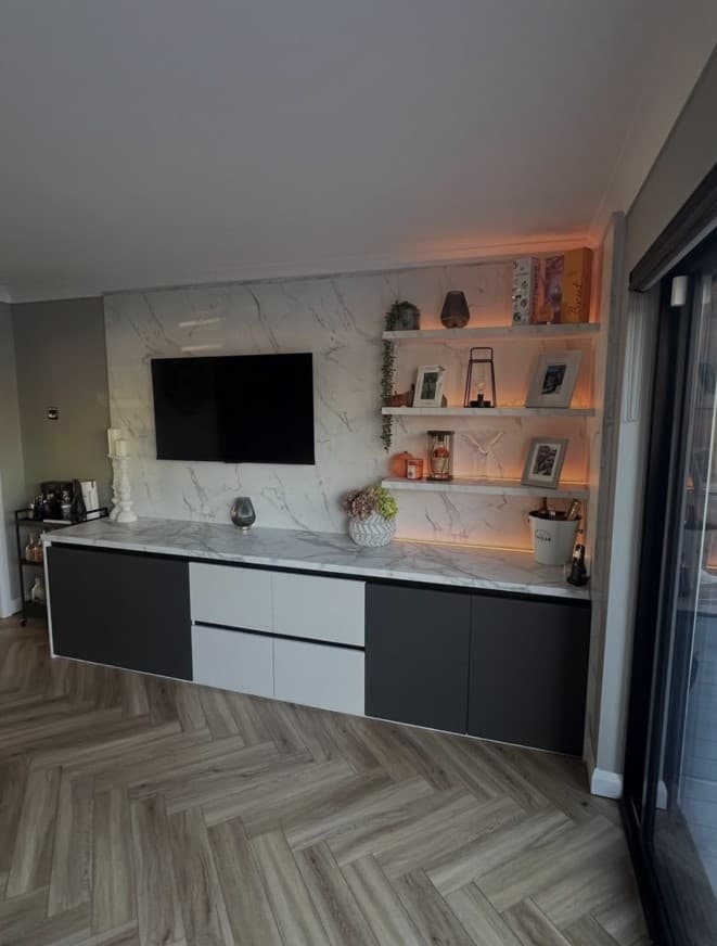 Calacatta marble media wall with floating anthracite cabinetry and illuminated display shelving.