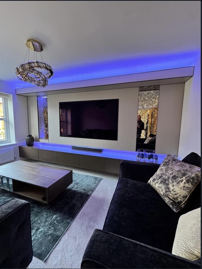 Living room view of the bespoke media wall illuminated in blue with a long floating cabinet beneath the television.