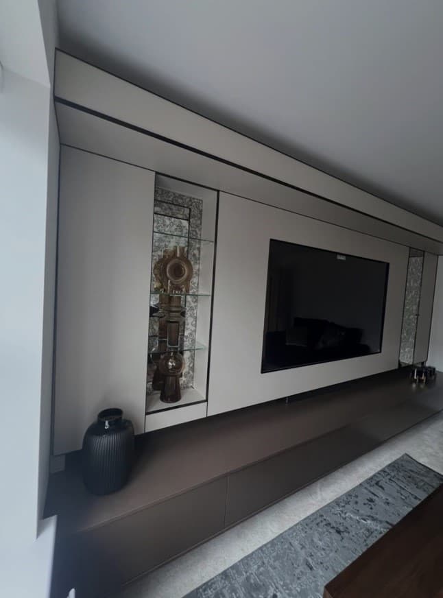 Angled close view of the fitted bronze cabinetry, beige wall panels and mirrored display shelving.