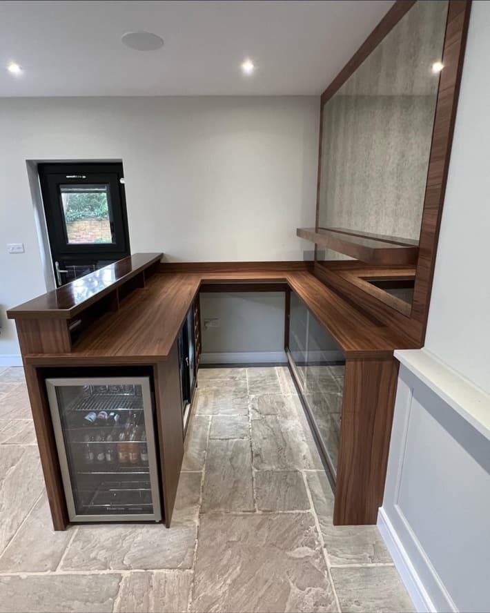 Inside view of the U-shaped bespoke bar with timber worktops, fitted storage and integrated drinks fridge.
