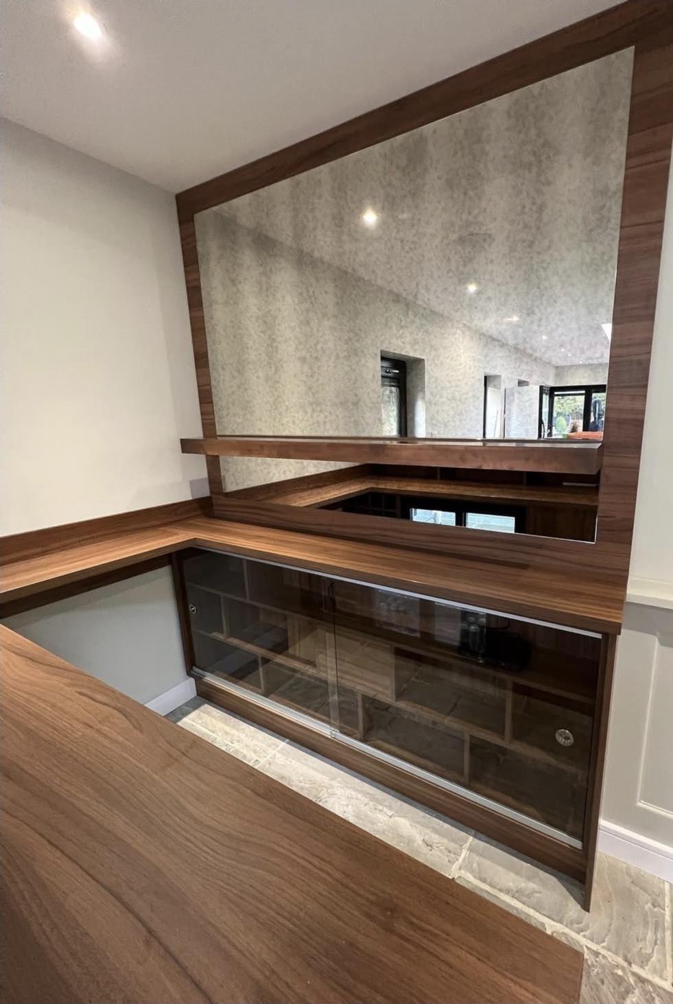 Bespoke bar joinery framed around a large Blenheim-style antique mirror with integrated glazed storage.