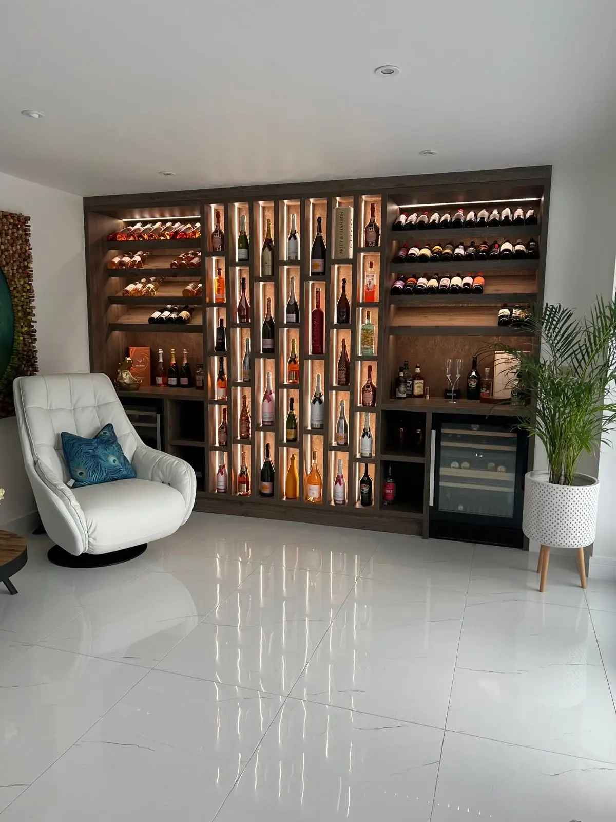 Front view of the dark timber wine display with illuminated bottle compartments, horizontal racks and wine coolers.
