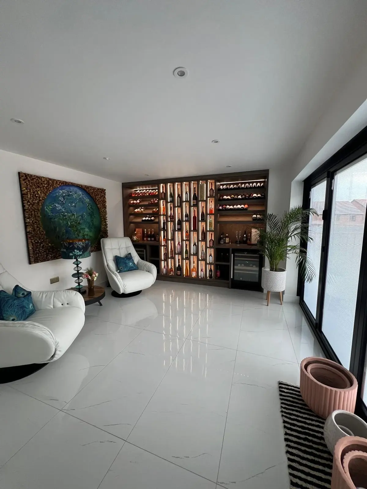 Wide room view of the fitted wine display beside seating and glazed doors.