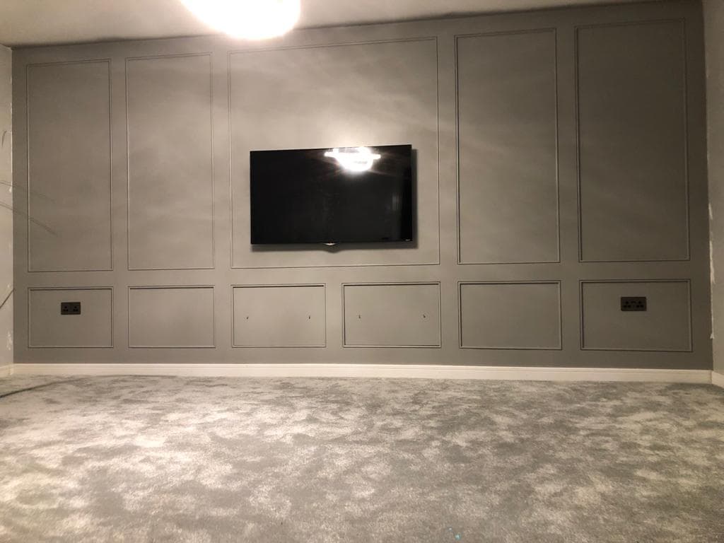 Finished grey MDF panelled television wall with symmetrical rectangular panelling.