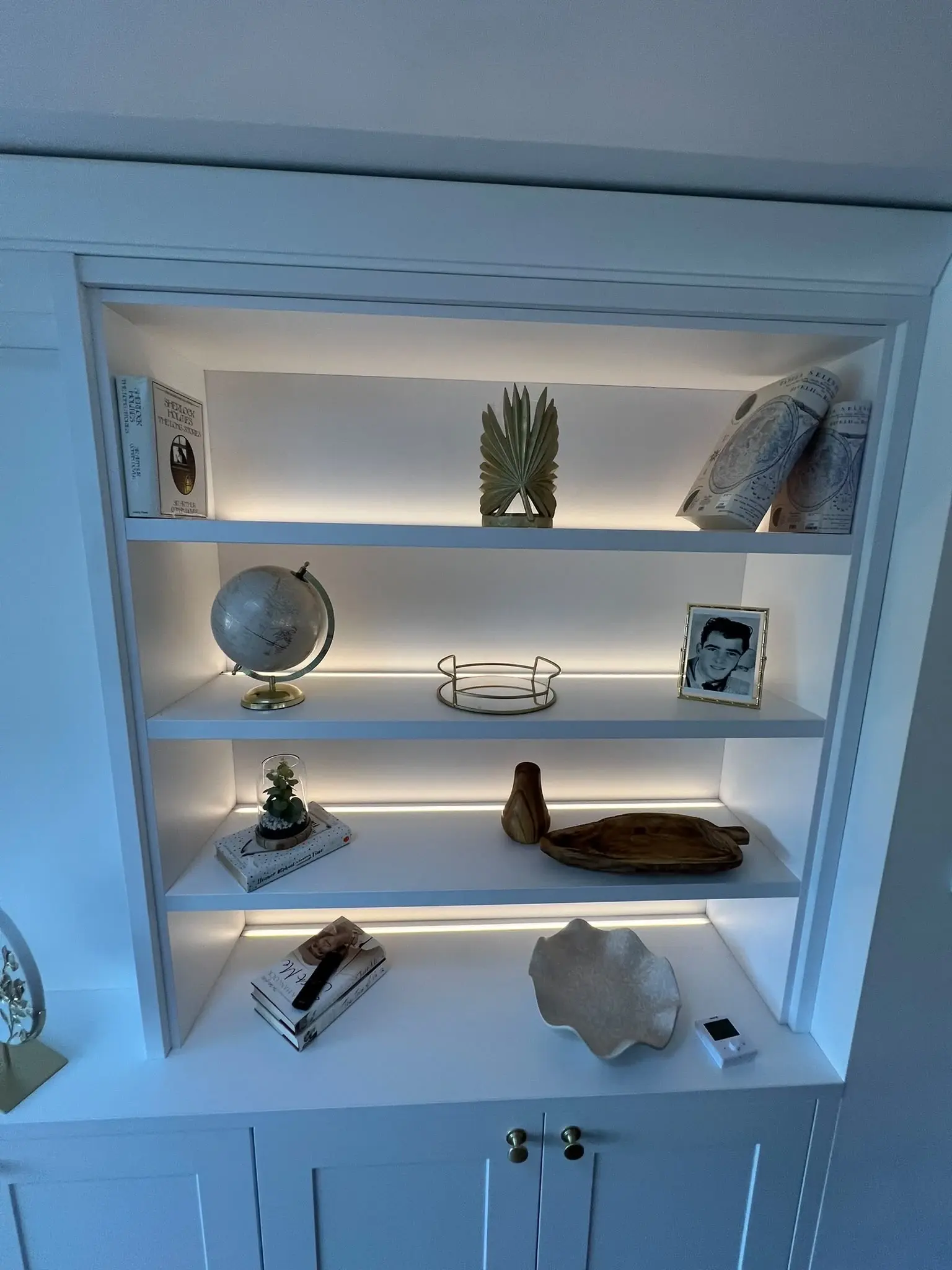 Right-hand illuminated display shelving above white fitted cupboards.