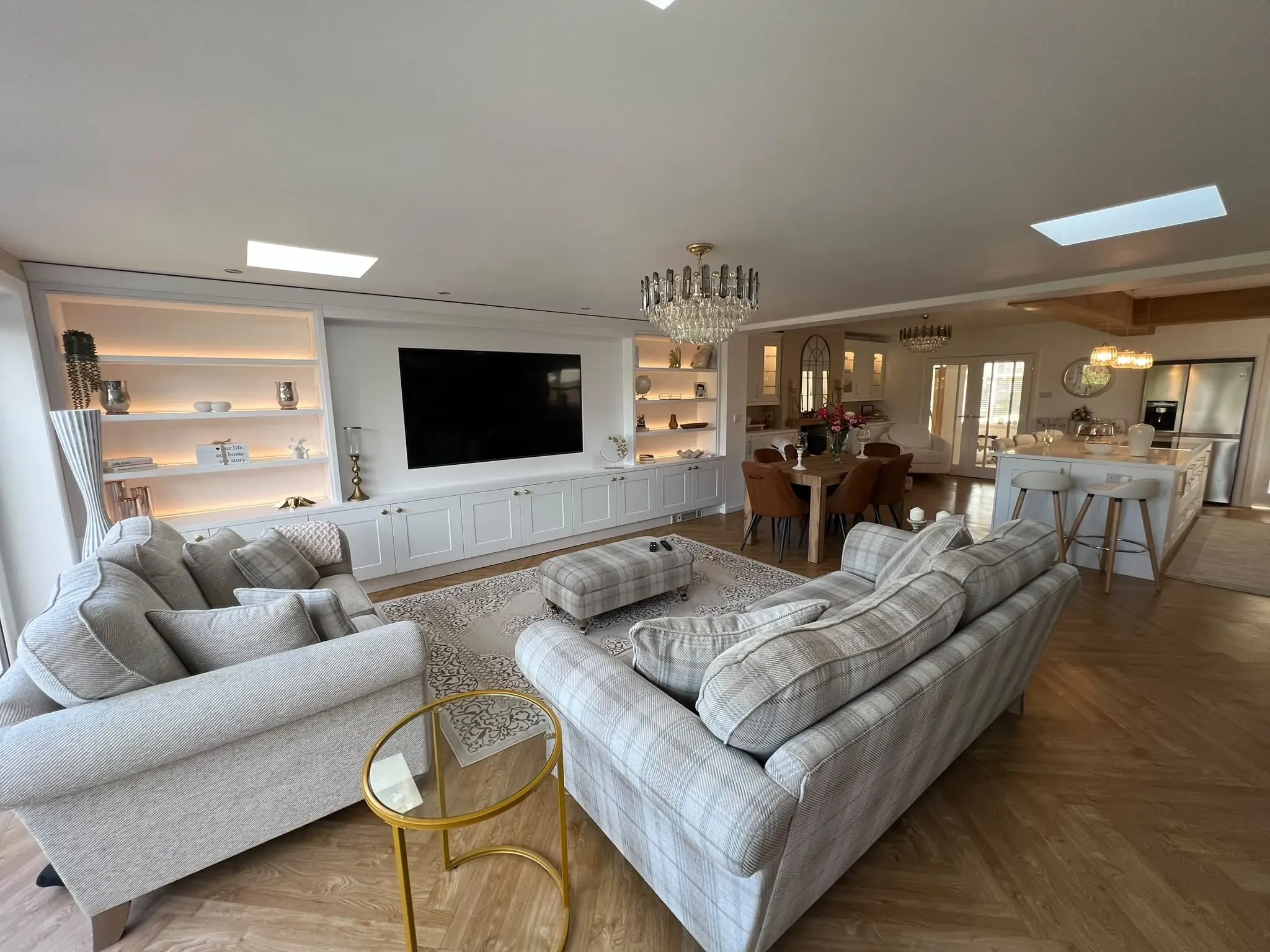 View across the seating area towards the white media wall, dining area and kitchen.