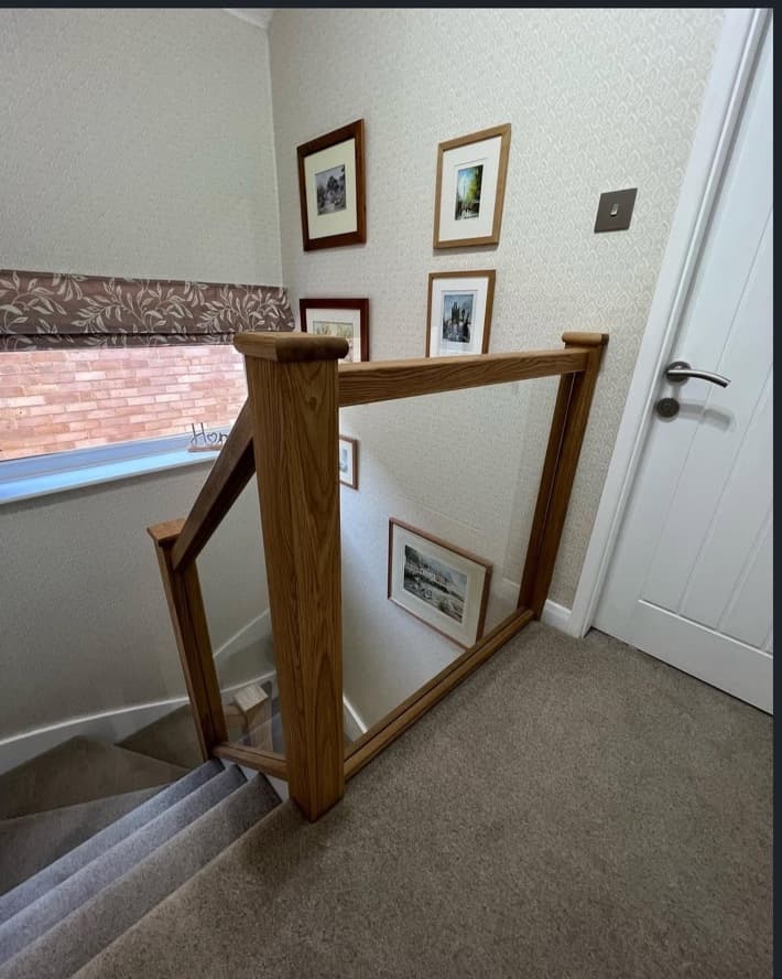 Upper landing with oak posts and a clear glass balustrade overlooking the staircase.