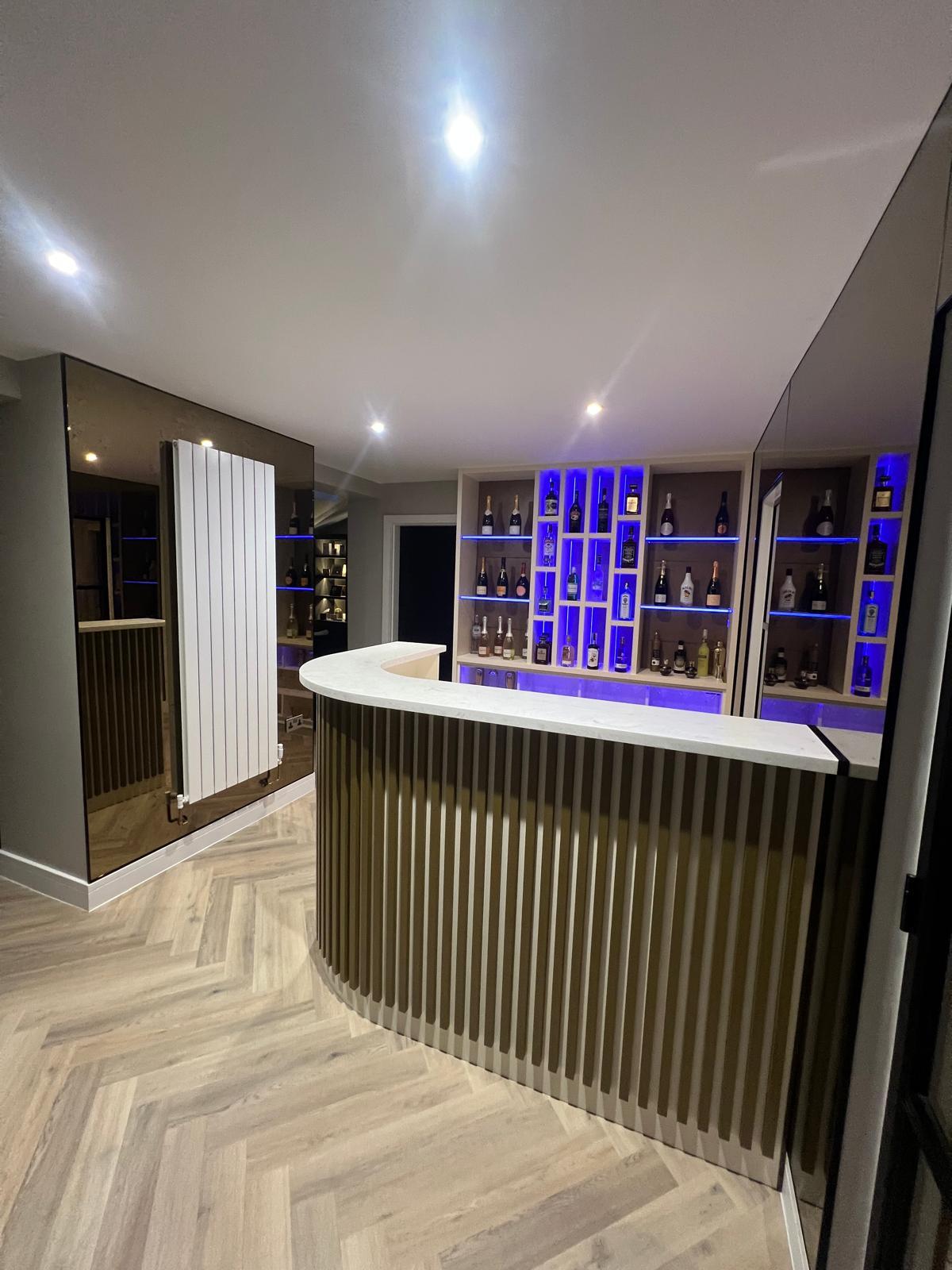 Bespoke home bar showing illuminated shelving and mirrored display panels.