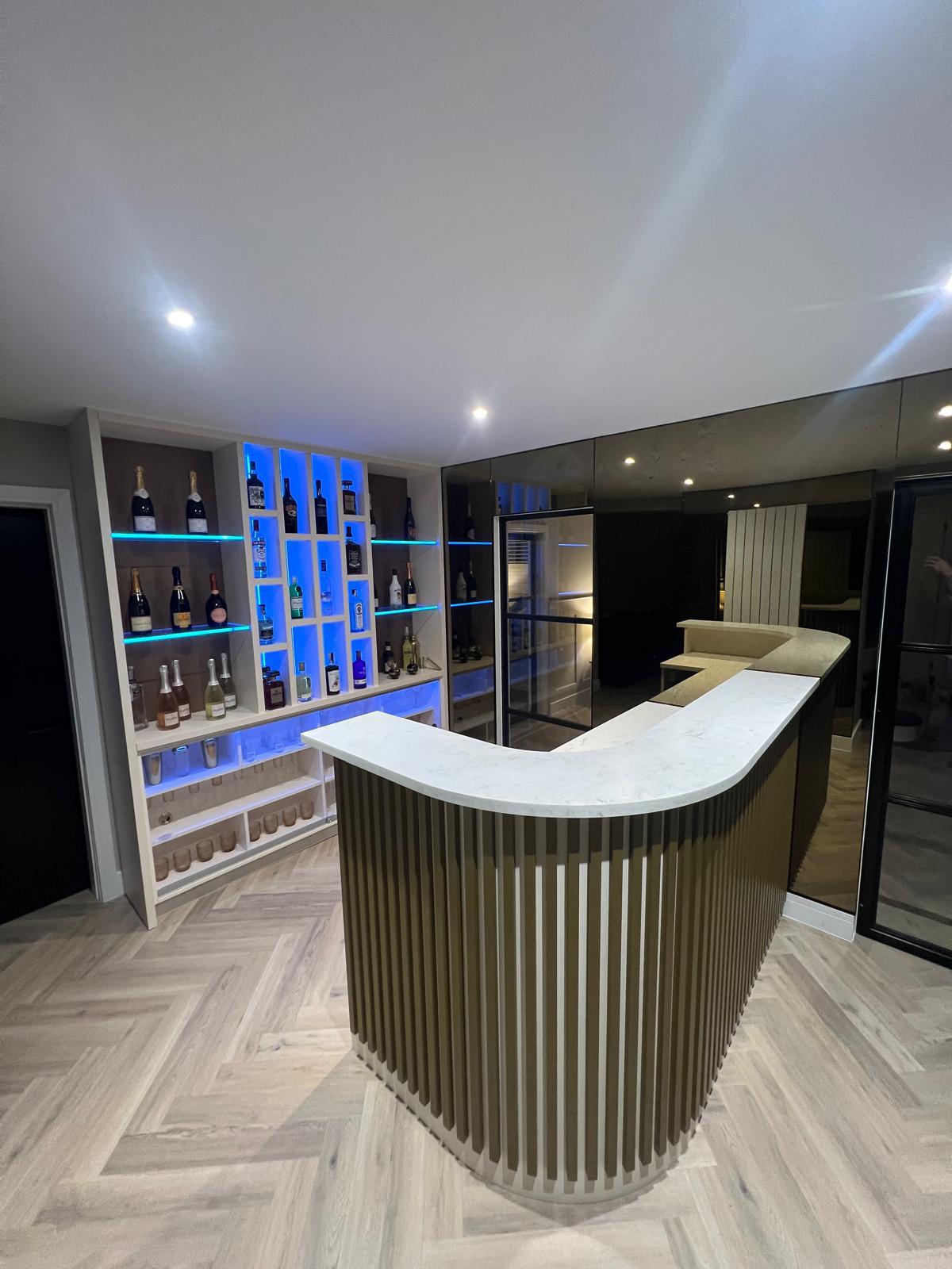 Illuminated bottle display within the bespoke home bar.